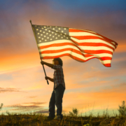 kid waving American flag at sunset
